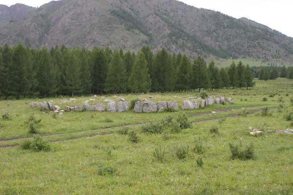 A low circle of rocks with trees and a mountain in the background