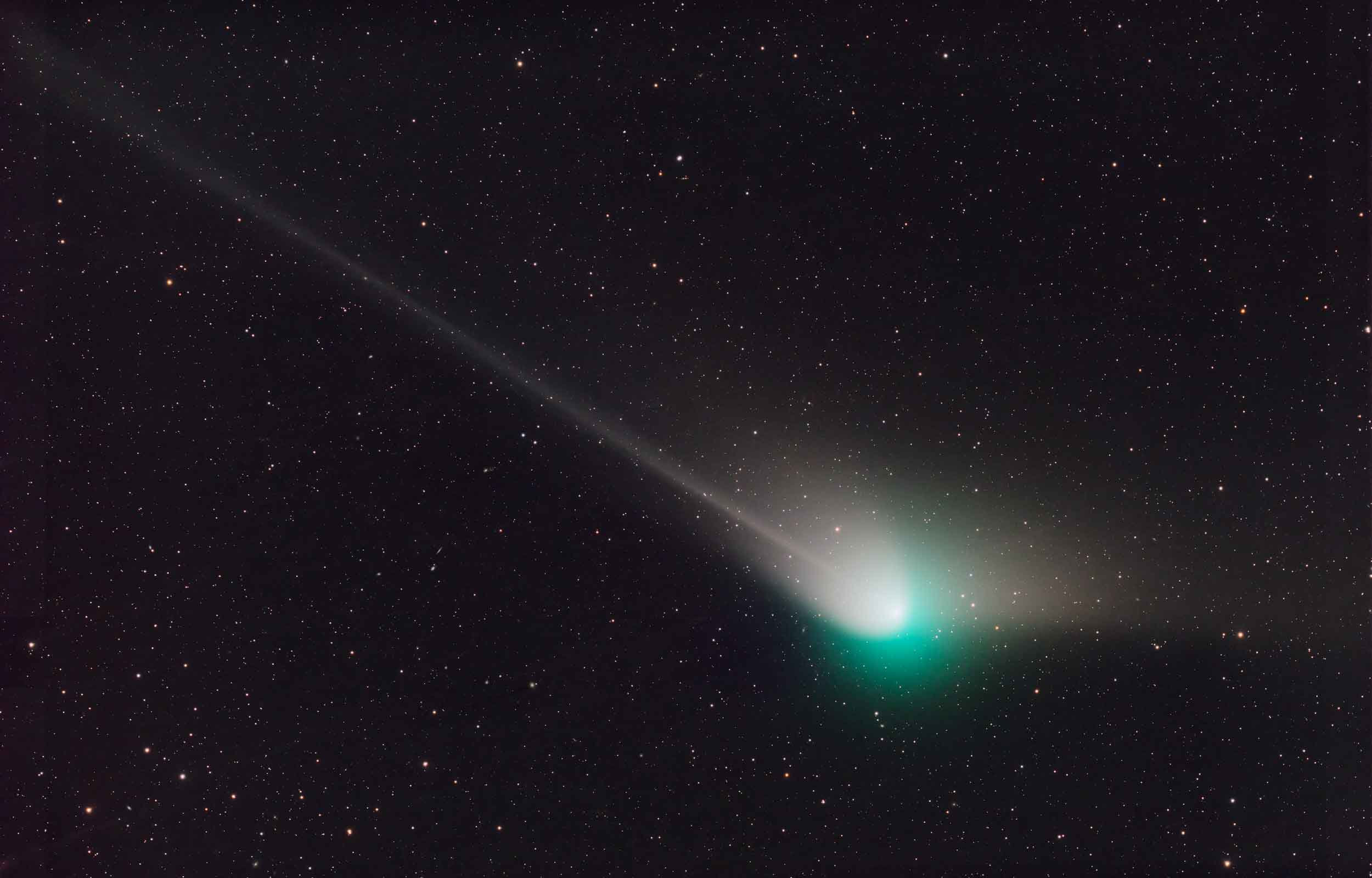 A comet with a green halo and tail against a starry background