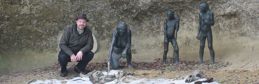 John Hawks next to three bronze Neandertals in the Krapina rockshelter