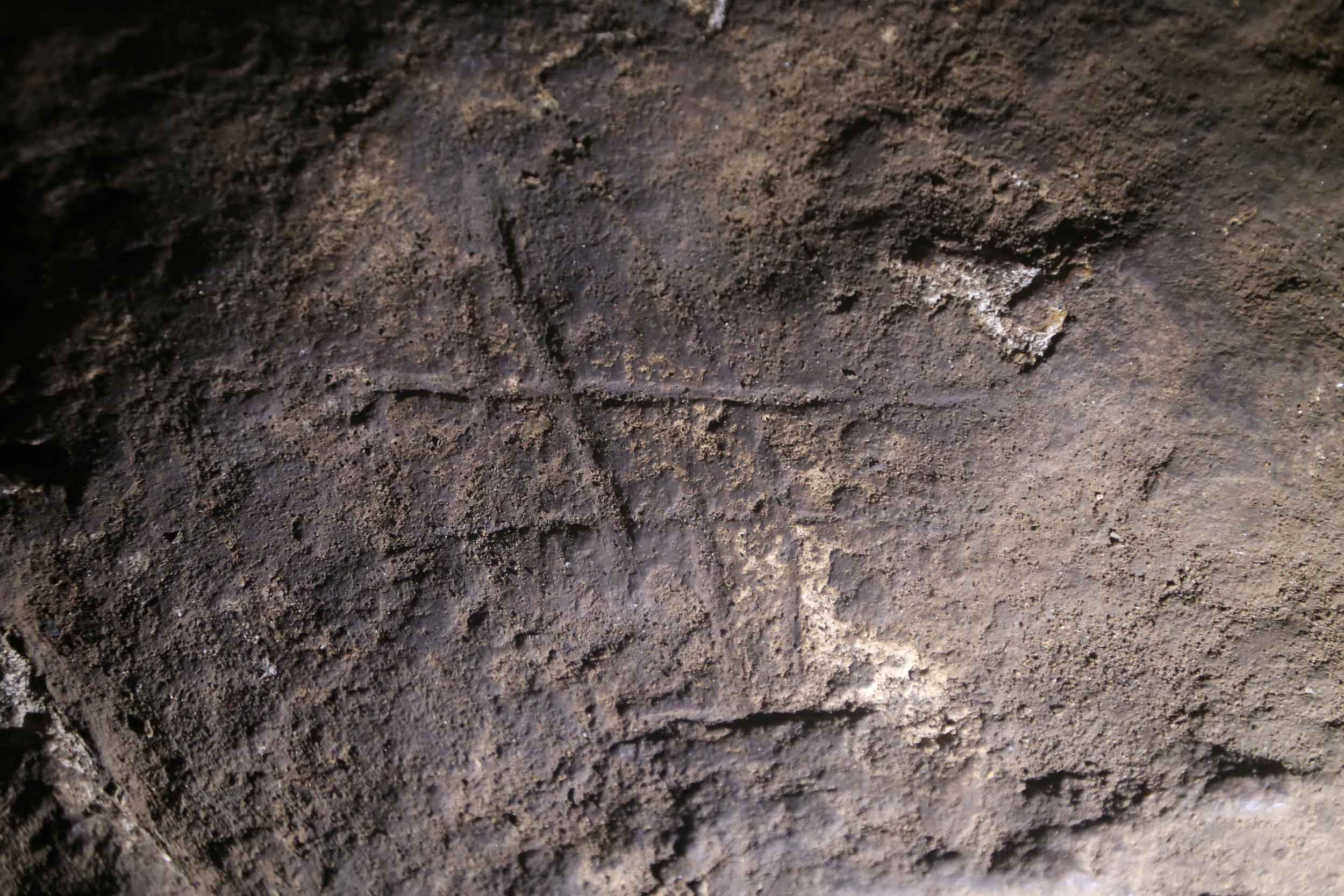 An engraved marking that resembles a hashtag on the floor of a cave