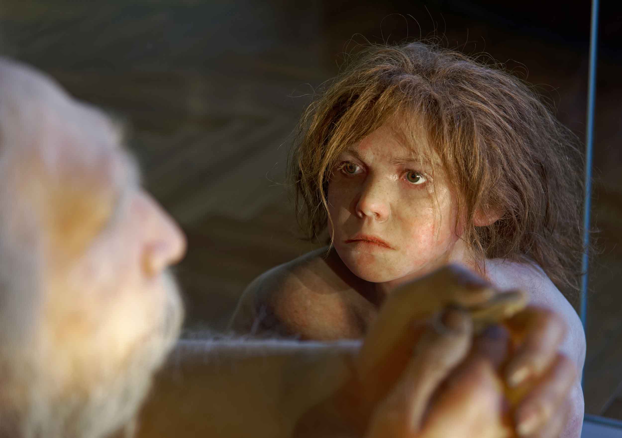 A child with vaguely Neandertal features looking up at an older man