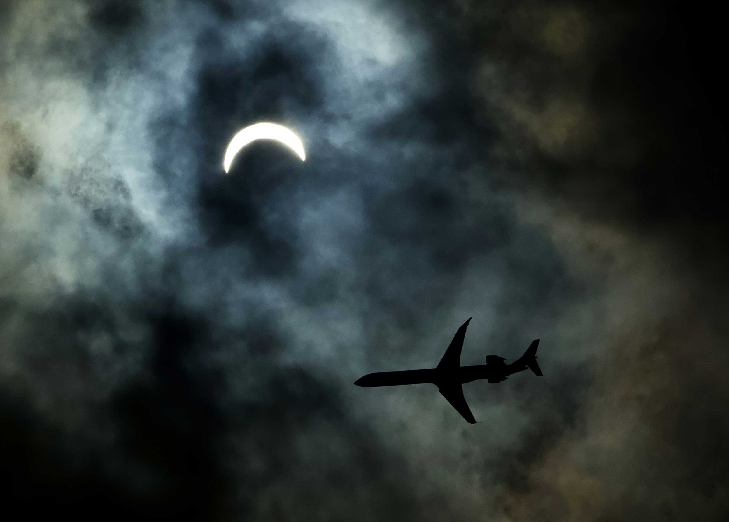 A commercial plane flies just beneath a partial solar eclipse