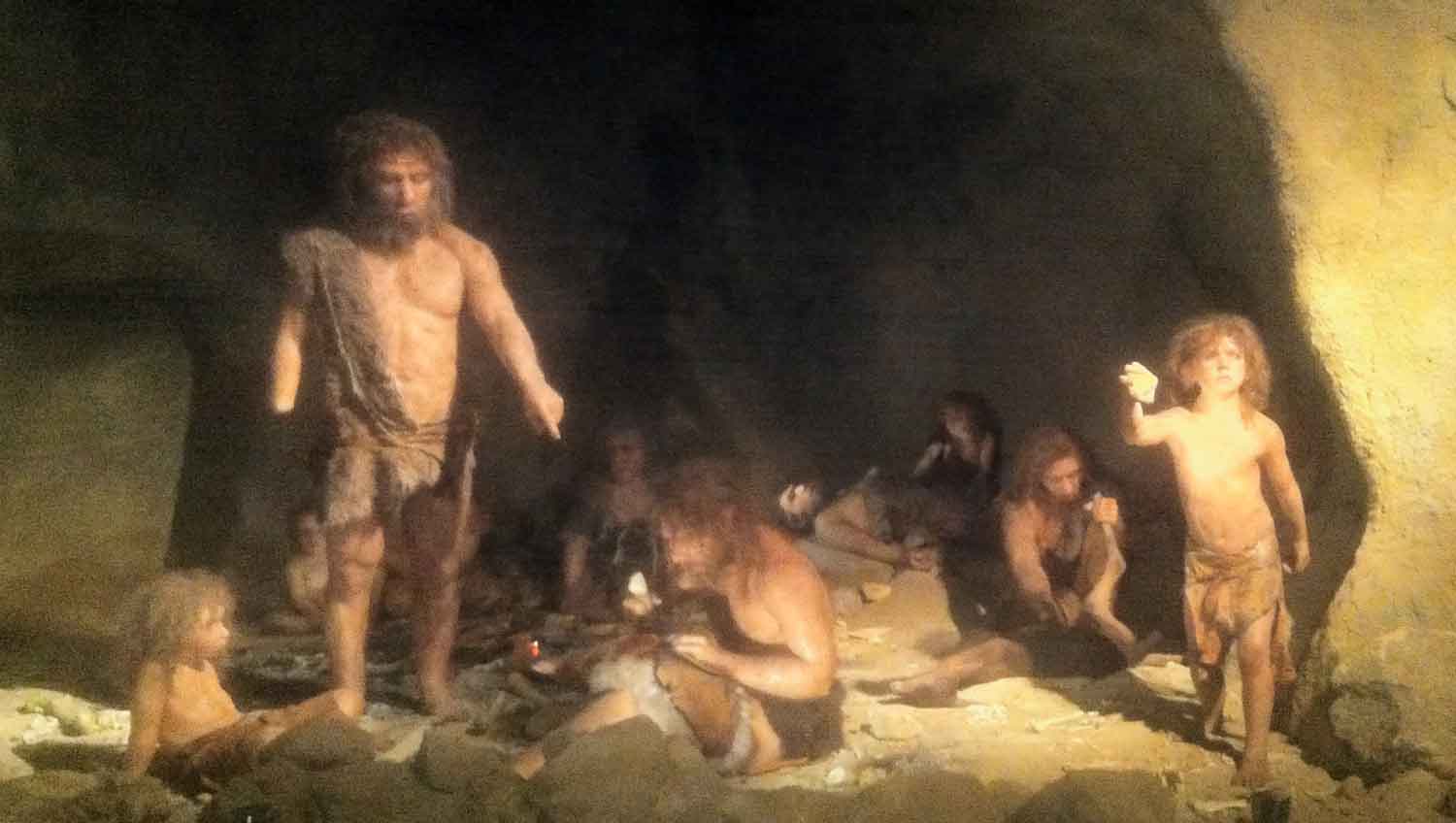 A group of Neandertals in a rockshelter with firelight