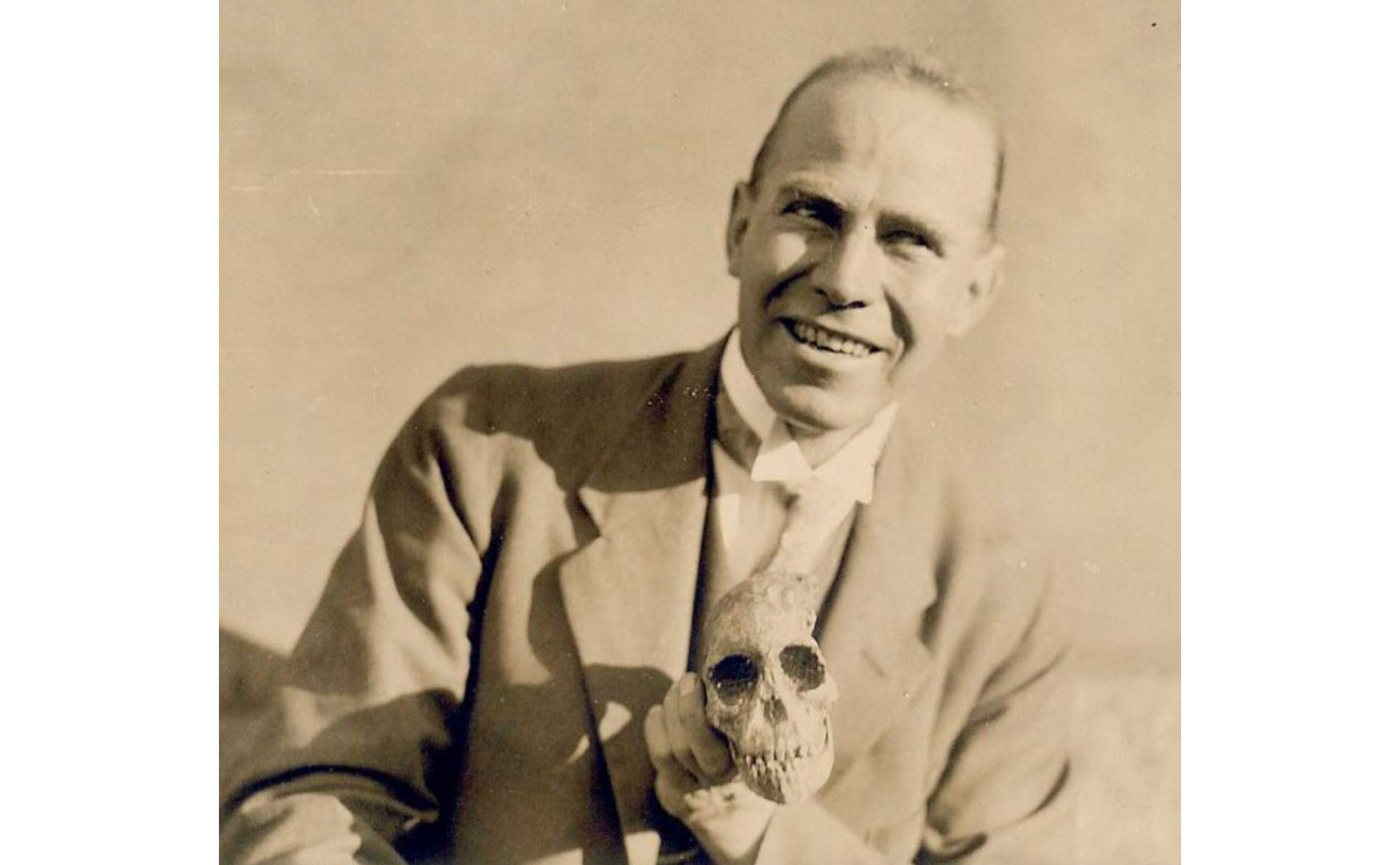 Smiling pose of Raymond Dart with Taung skull held in his hand