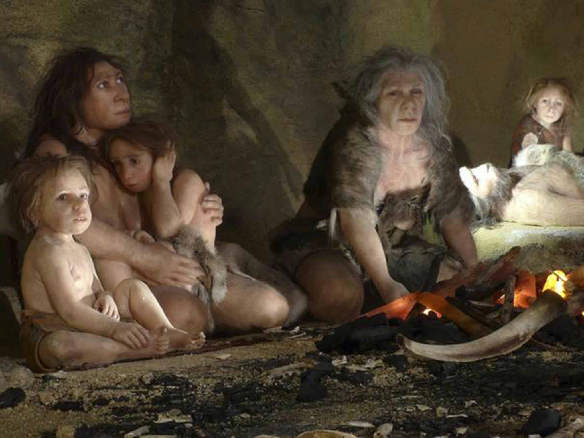 A Neandertal woman with two children clinging to her, an older woman tends a fire and a child looks on from the background